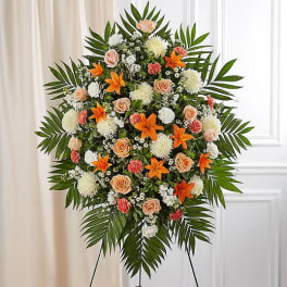 Standing floral spray with orange lilies, peach roses, and white blooms