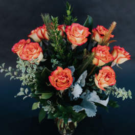 Orange and cream roses arranged in a glass vase