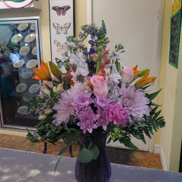 Mixed bouquet of pink, purple, and orange flowers in a dark vase