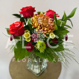 Bouquet of red roses and mixed mums in a glass vase