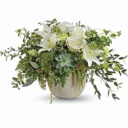 White roses and lilies in a beige vase with trailing greenery