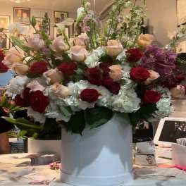 Large mixed flower arrangement in a white hat box with red and blush roses