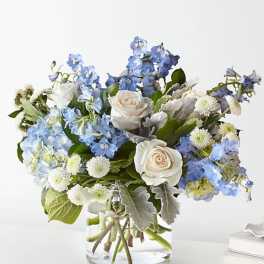Blue and white flowers arranged in a clear glass vase