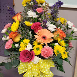 Colorful mixed bouquet with roses, daisies, carnations, and a yellow polka-dot ribbon