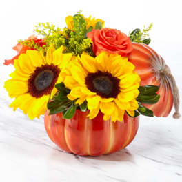 Sunflowers and roses arranged in a pumpkin-shaped container