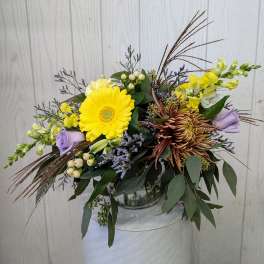 Mixed bouquet with yellow gerbera, lavender roses, and chrysanthemums in a glass vase