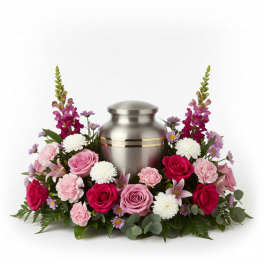 Pink and white flowers arranged around a silver urn