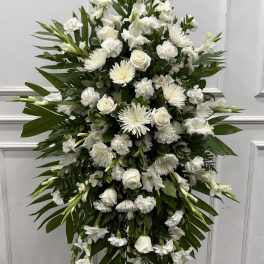 Tall white funeral spray with roses, chrysanthemums, and lilies
