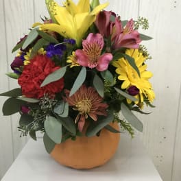 Colorful mixed bouquet in an orange vase with lilies, daisies, and carnations
