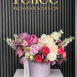 Pink, white, and cream roses arranged in a round lavender box