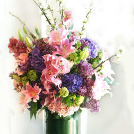 Tall bouquet of pink lilies and purple hydrangeas in a glass vase