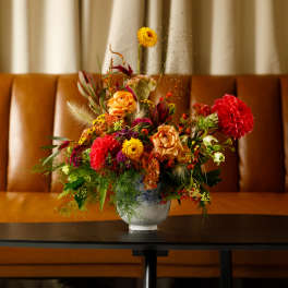 Colorful mixed flower arrangement in a white vase on a table