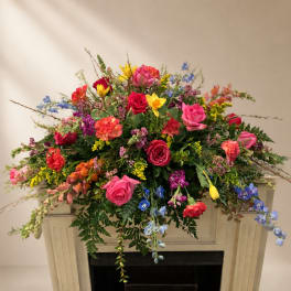 Large colorful floral arrangement with roses and mixed blooms on a mantel