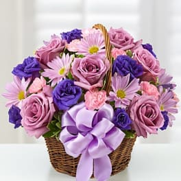 Basket of pink and purple flowers with a lavender ribbon bow
