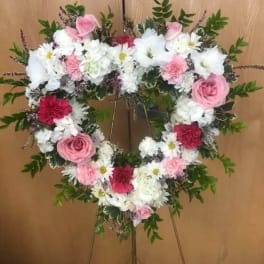 Heart-shaped floral wreath on an easel with pink and white flowers