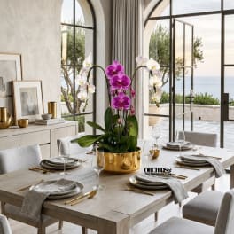 Potted orchid arrangement in a gold container on a set dining table