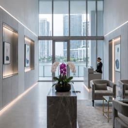 Potted white and purple orchids on a marble pedestal in a modern lobby