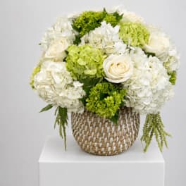 White and green floral arrangement in a woven basket