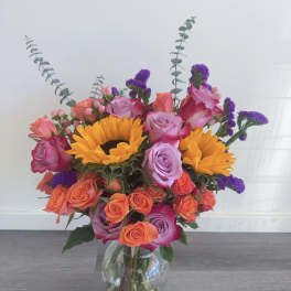 Mixed bouquet of roses and sunflowers in a clear glass vase