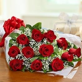 Bouquet of red roses wrapped in white paper with a red bow
