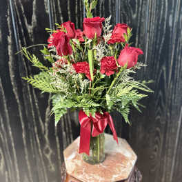 Red roses and carnations in a glass vase with a red ribbon