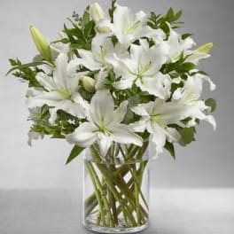 White lilies arranged in a clear glass vase