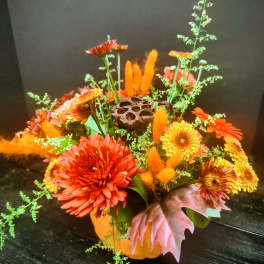 Orange and yellow chrysanthemum arrangement in a pumpkin container