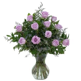 Lavender roses in a clear glass vase with mixed greenery