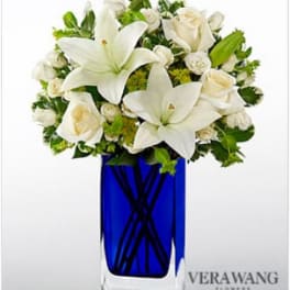 White lilies and roses arranged in a blue glass vase