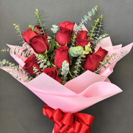 Bouquet of red roses wrapped in pink paper with a red ribbon