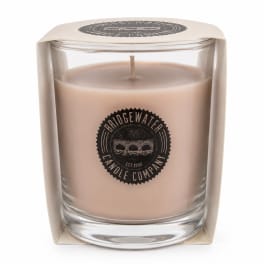 Beige candle in a clear glass container with boxed packaging