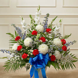 Large floral arrangement with red and white blooms and a blue ribbon bow