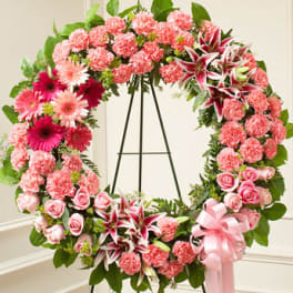 Pink floral wreath on a black stand with a ribbon bow