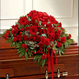 Red floral casket spray with ribbon on a wooden casket