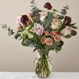 Mixed bouquet of pink and cream roses in a clear glass vase