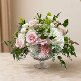 Pink and white roses with hydrangeas in a clear pedestal vase