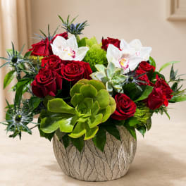 Red roses and white orchids arranged with succulents in a textured vase