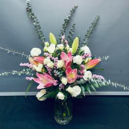 Pink and white floral arrangement with lilies and roses in a glass vase