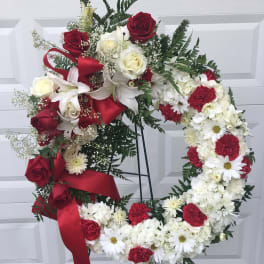 Red and white floral wreath on a stand with ribbon