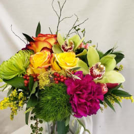 Bright mixed bouquet with roses, orchids, and a glass vase
