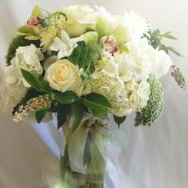 White floral bouquet in a glass vase with a ribbon tie