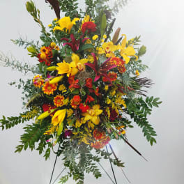 Large standing floral spray with yellow lilies and red-orange blooms