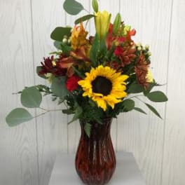 Mixed bouquet with a sunflower in a brown glass vase