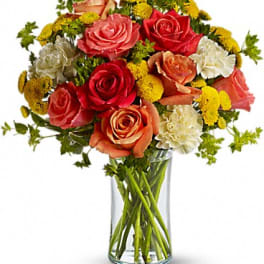 Bouquet of red, pink, and peach roses in a clear glass vase