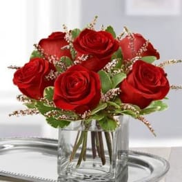 Red roses arranged in a clear glass vase