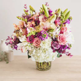 Mixed bouquet of pink, white, and purple flowers in a glass vase