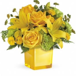 Yellow roses and lilies arranged in a square glass vase