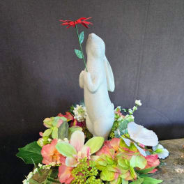 White rabbit figurine surrounded by pastel flowers and a red bloom on top