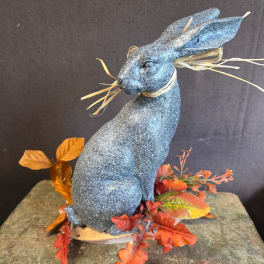Blue glitter rabbit figurine with autumn leaves on a stone base
