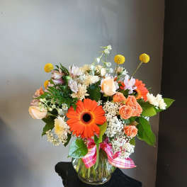 Mixed bouquet in a glass vase with orange gerberas and peach roses